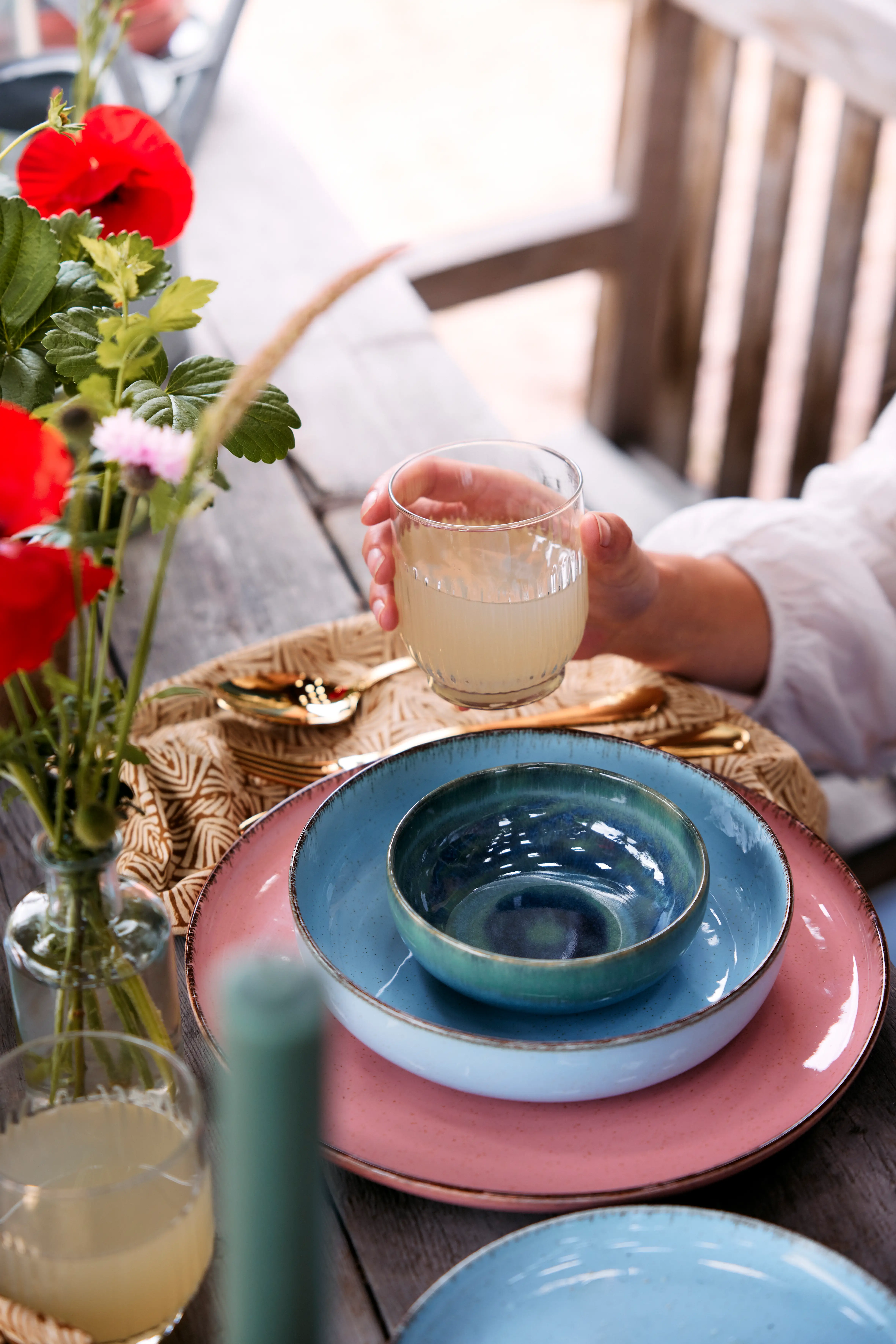 Hand holding a glass above stacked colorful ceramic plates
