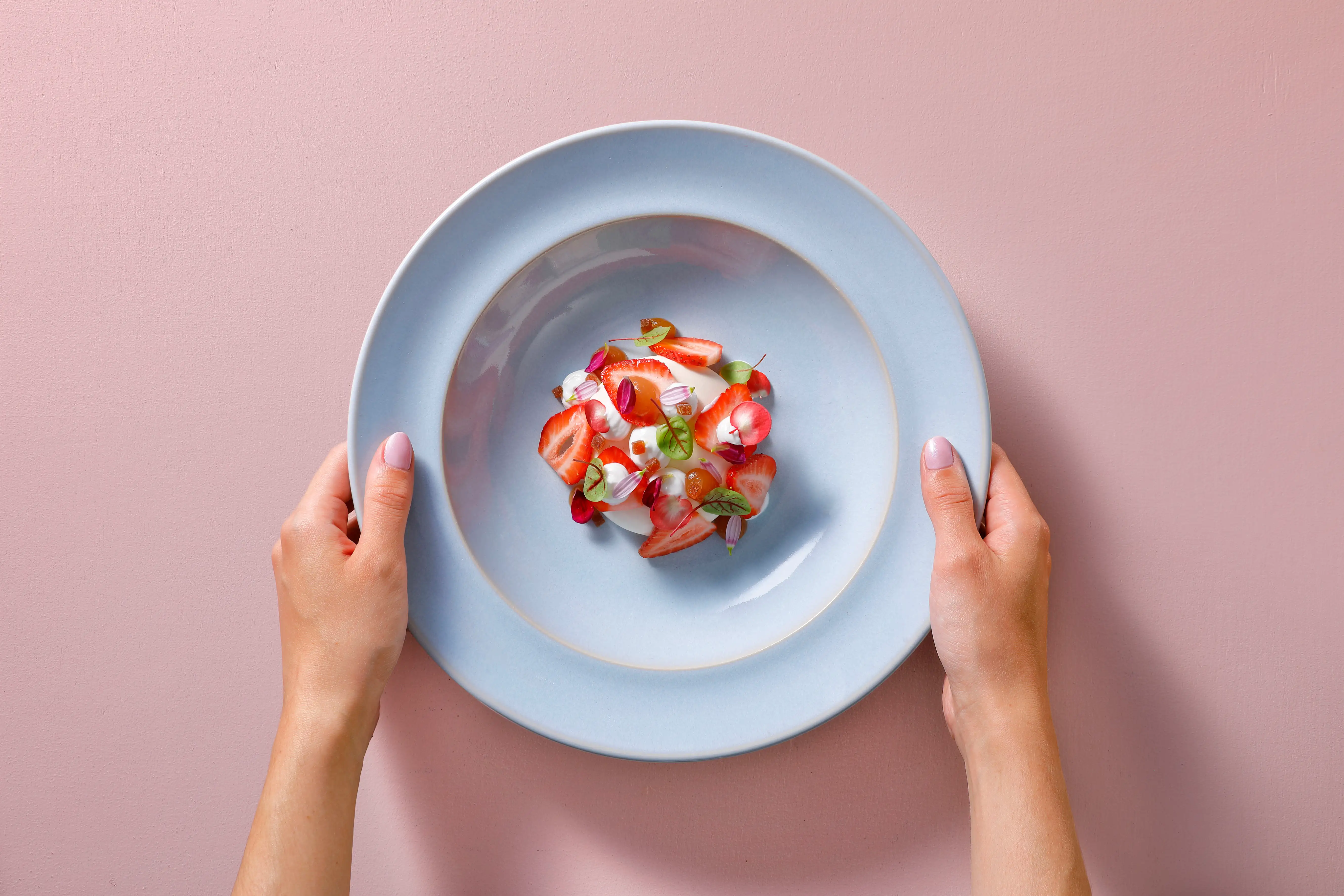 Two hands holding a gray plate with a dessert