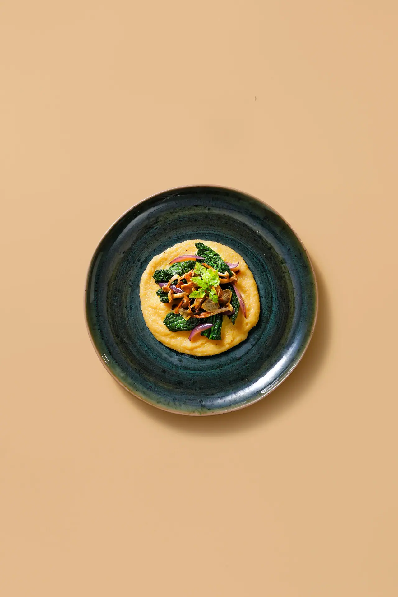 Plate with creamy yellow polenta topped with sautéed kale