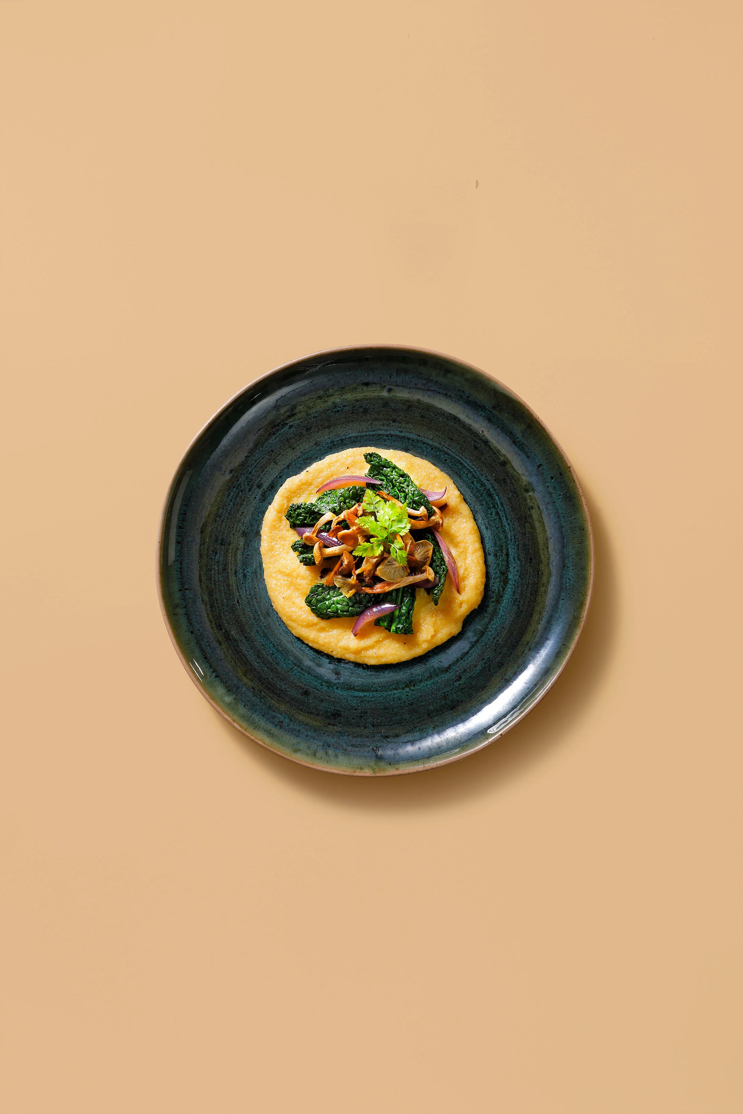 Plate with creamy yellow polenta topped with sautéed kale