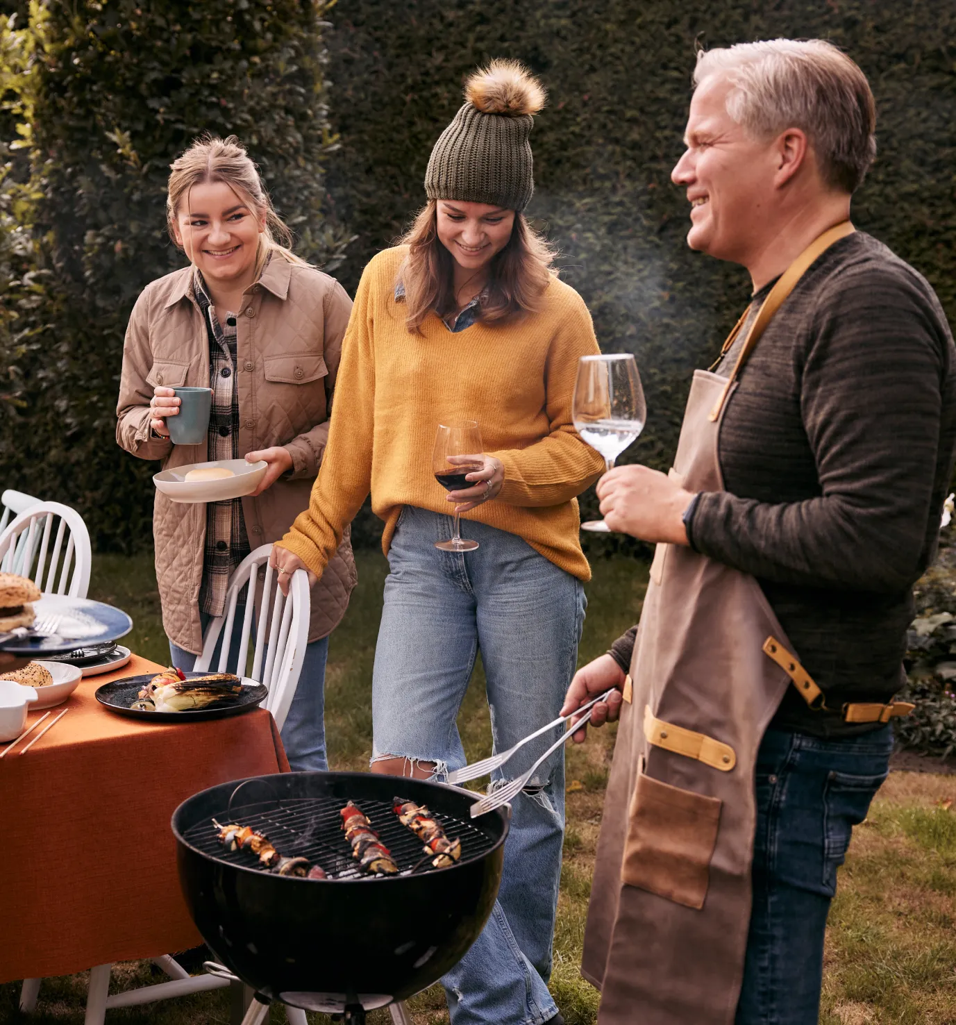 Three people enjoying a backyard barbecue