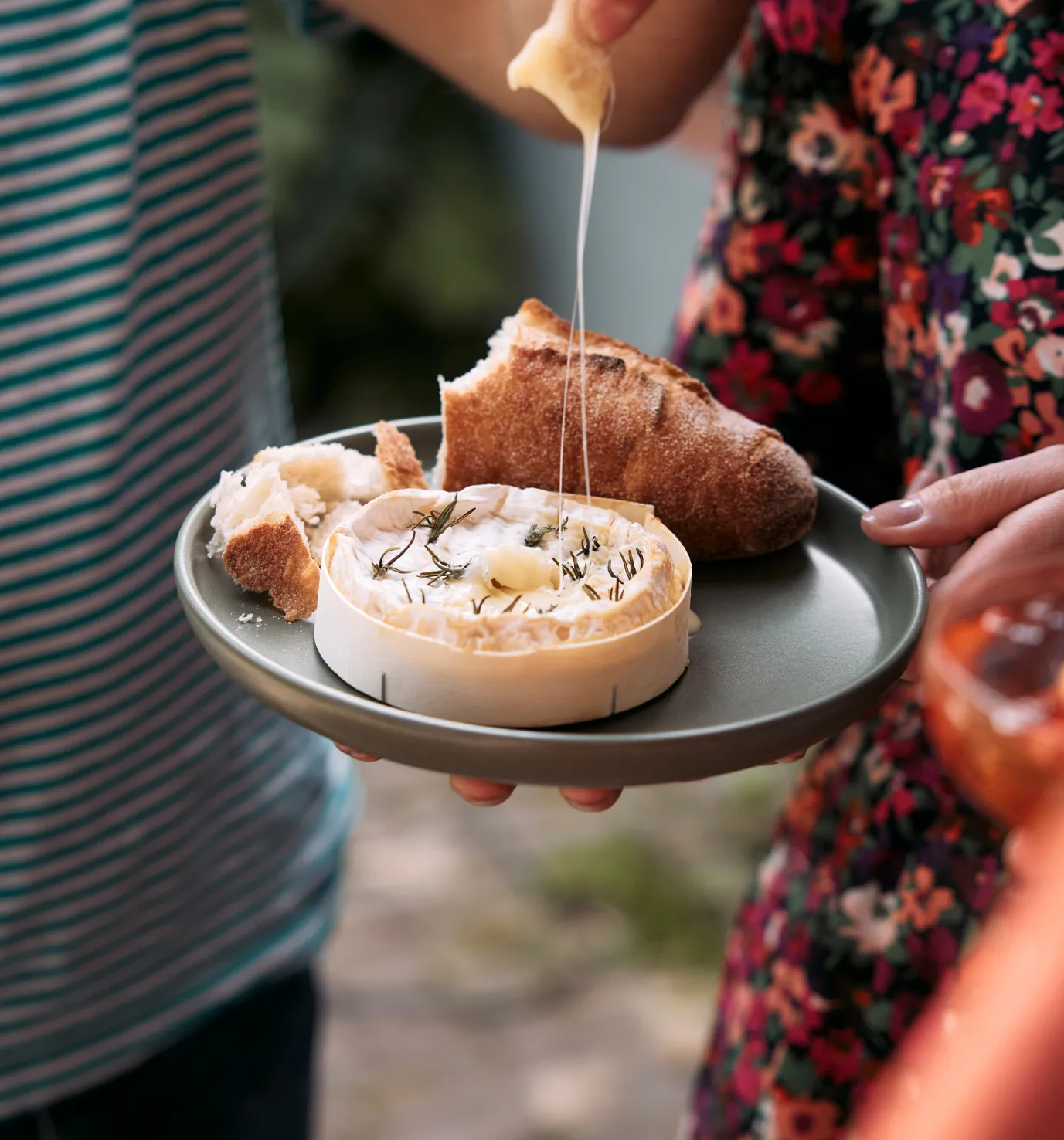 Person holding a plate with baked cheese